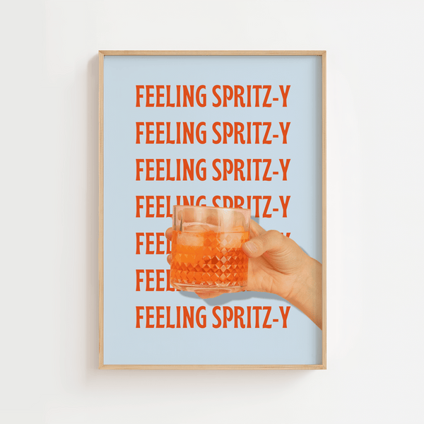 Plakat med teksten "Feeling Spritz-y" i rød-orange skrift gentaget på lyseblå baggrund, med en hånd der holder et glas Aperol Spritz.