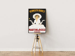 Vintage plakat med elegant kvinde i hvid kjole og hat, reklame for Vermouth Bianco fra Martini & Rossi, sort baggrund og rød tekst.

