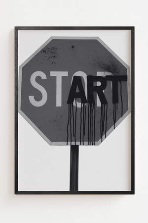 Sort hvid plakat med stopskilt hvor ordet START er spraymalet med graffiti
