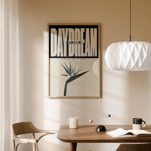 Daydream plakat med stor beige typografi, japansk tekst og stiliseret blomst i egetræsramme over spisebord