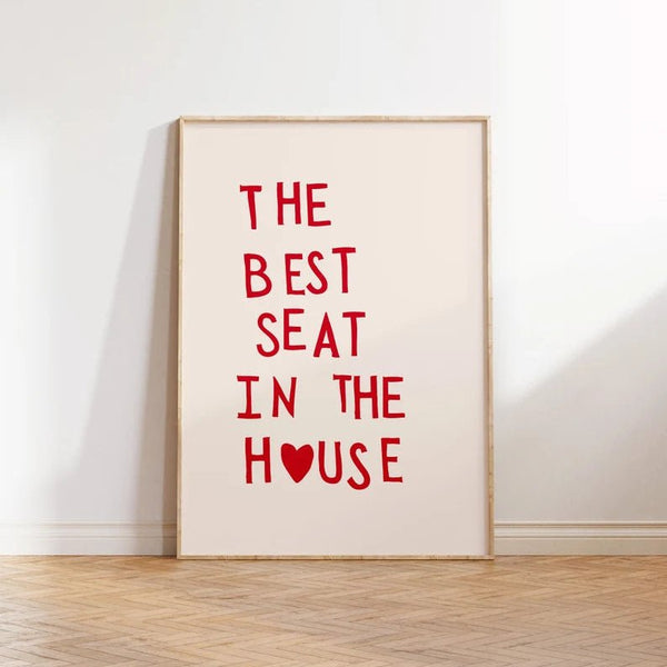 Plakat med rød tekst “The Best Seat in the House” og hjerte – humoristisk vægkunst til badeværelse eller gæstetoilet, indrammet og opstillet i moderne interiør.