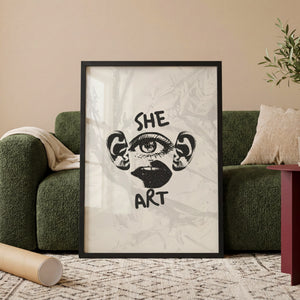 She Art plakat med grafiske ansigtsdetaljer og tekst i sort hvid i egetræsramme ved sofa