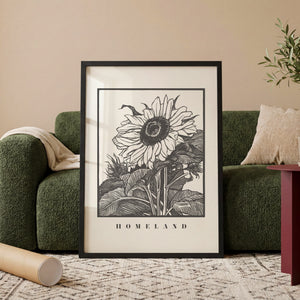 Solsikke Homeland plakat med grafisk blomstermotiv i sort hvid i egetræsramme ved sofa